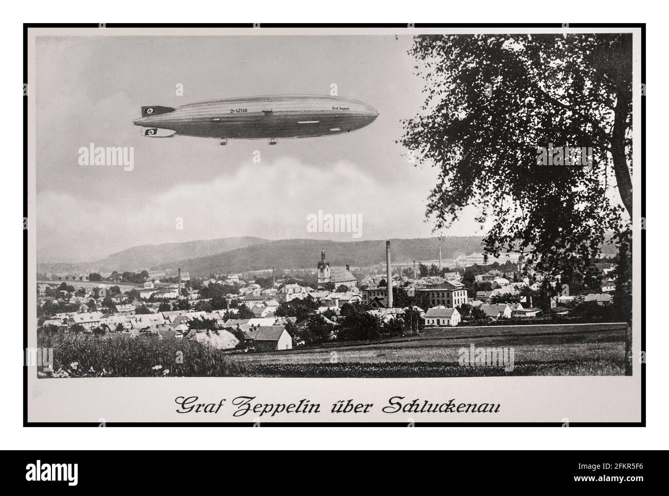 Vintage 1930's Graf Zeppelin Air Ship Balloon with Swastika tail fin over a small town in Germany Schluckenau. 'GRAF ZEPPELIN UBER SCHLUCKENAU' Stock Photo