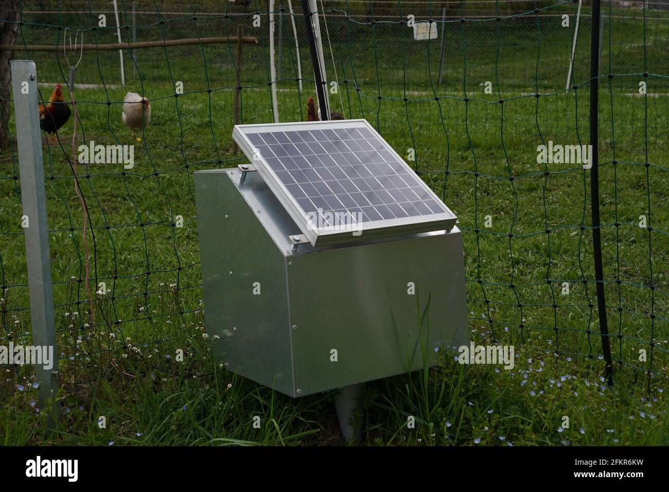 Electric fence with solar panel. The fence surrounds poultry farm with