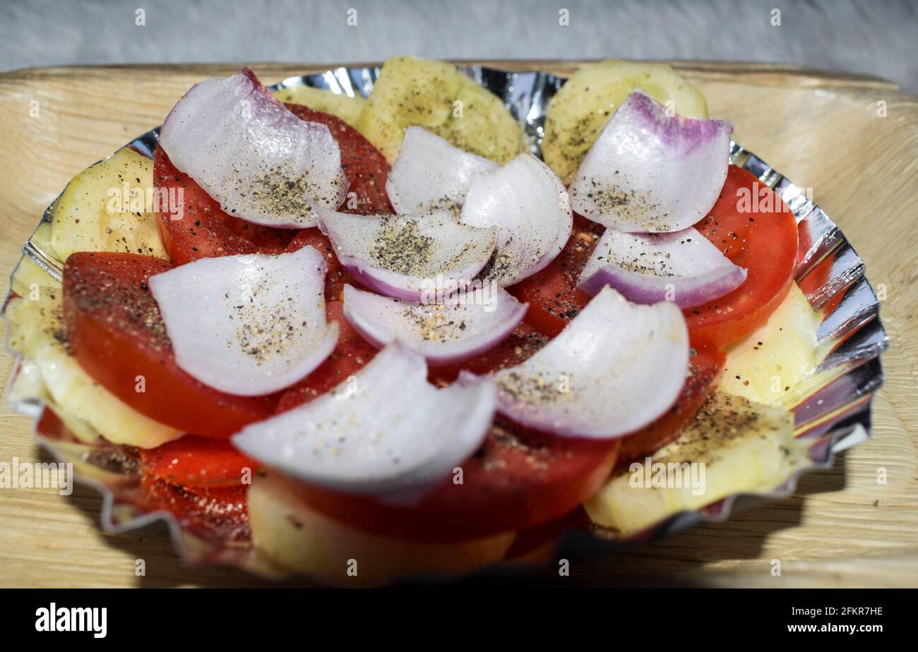 Raw onion, tomato and cucumber salad. Masala powder and black pepper sprinkled and served in plate. Indian street food snacks salad Stock Photo