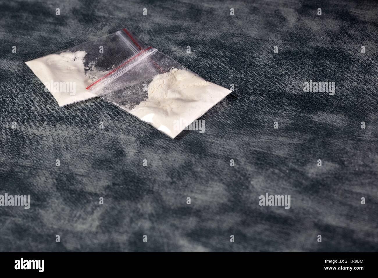Transparent plastic bags with white powder, cocaine,speed or other drugs on gray background with copy space, dealing,drug,junky,addiction concept Stock Photo