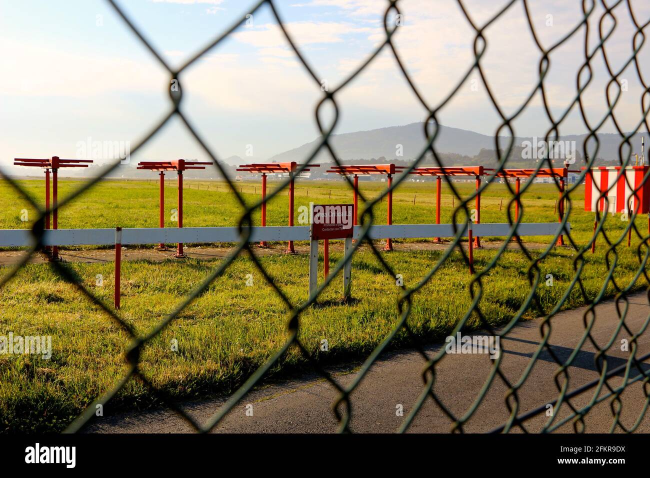 ILS localiser antenna array at the end of the runway seen through the security fence at Santander Airport Cantabria Spain Morning sun Stock Photo