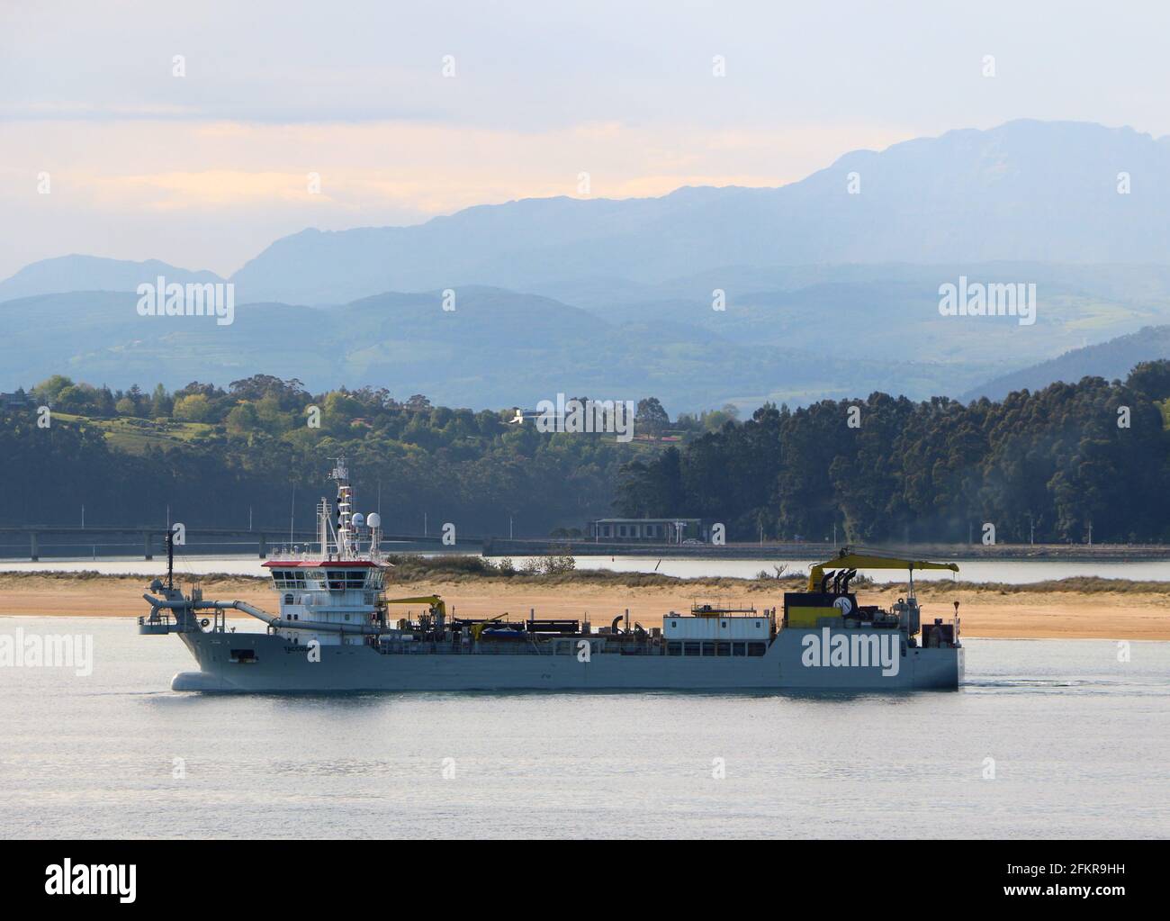 The Taccola hopper dredger working to move sand in the bay of Santander Cantabria Spain on a calm spring morning Stock Photo