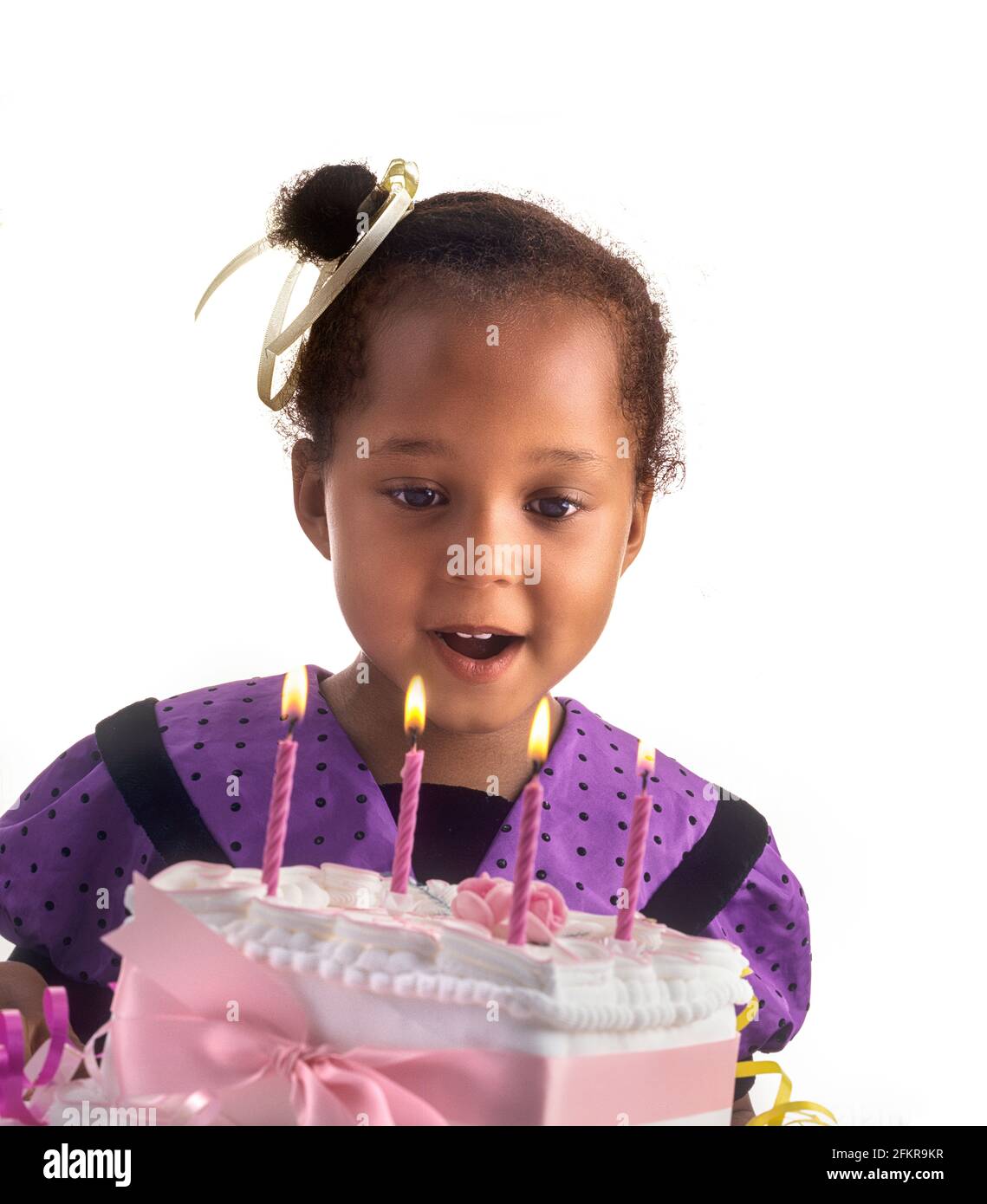 INFANT HAPPY Birthday Cake candles 4 years old cute pretty British African Afro Caribbean girl celebrating with her special birthday cake making a wish about to blow out the four candles, White Cutout background Stock Photo