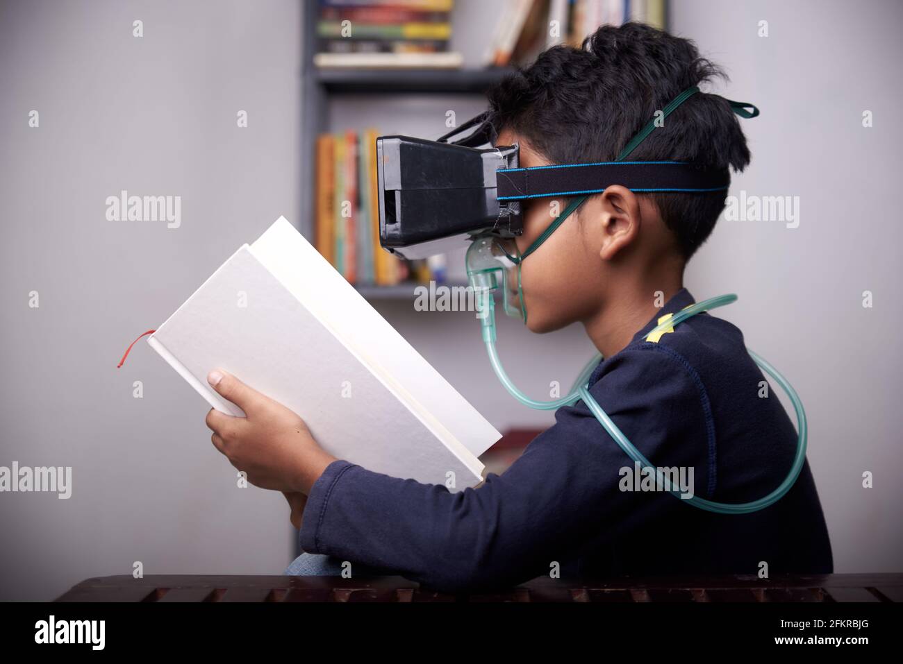 little Boy wearing VR headset and nebulizer mask studying at home quarantine Stock Photo