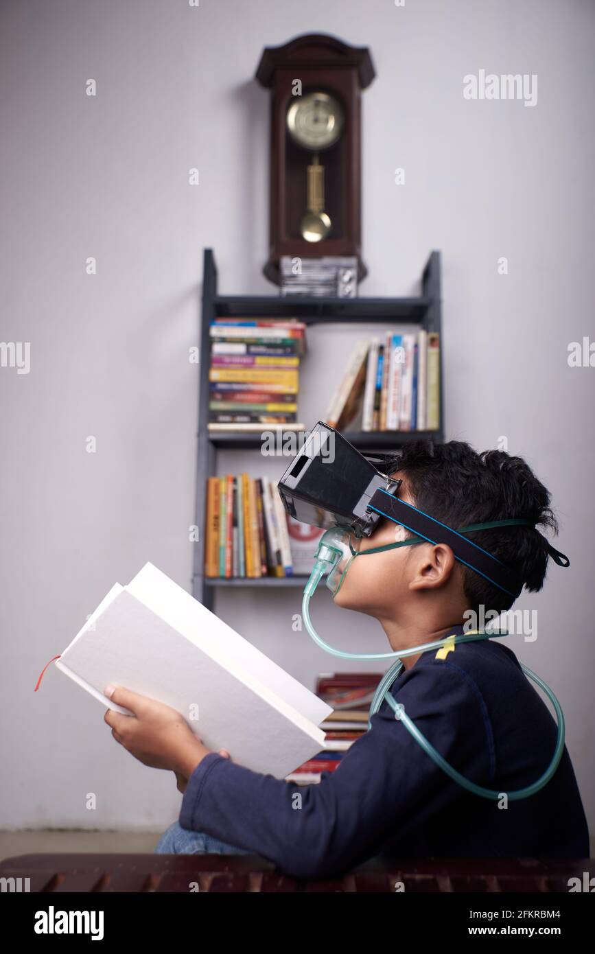 little Boy wearing VR headset and nebulizer mask studying at home quarantine Stock Photo