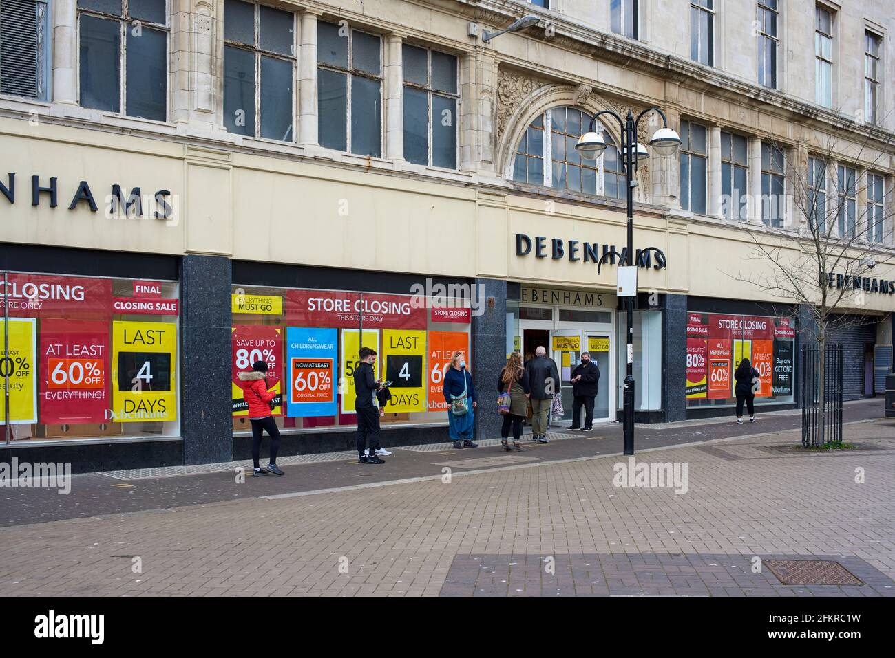 People standing in a queue outside the Hastings branch of Debenhams, East Sussex, prior to permanent closure, in May 2021 Stock Photo