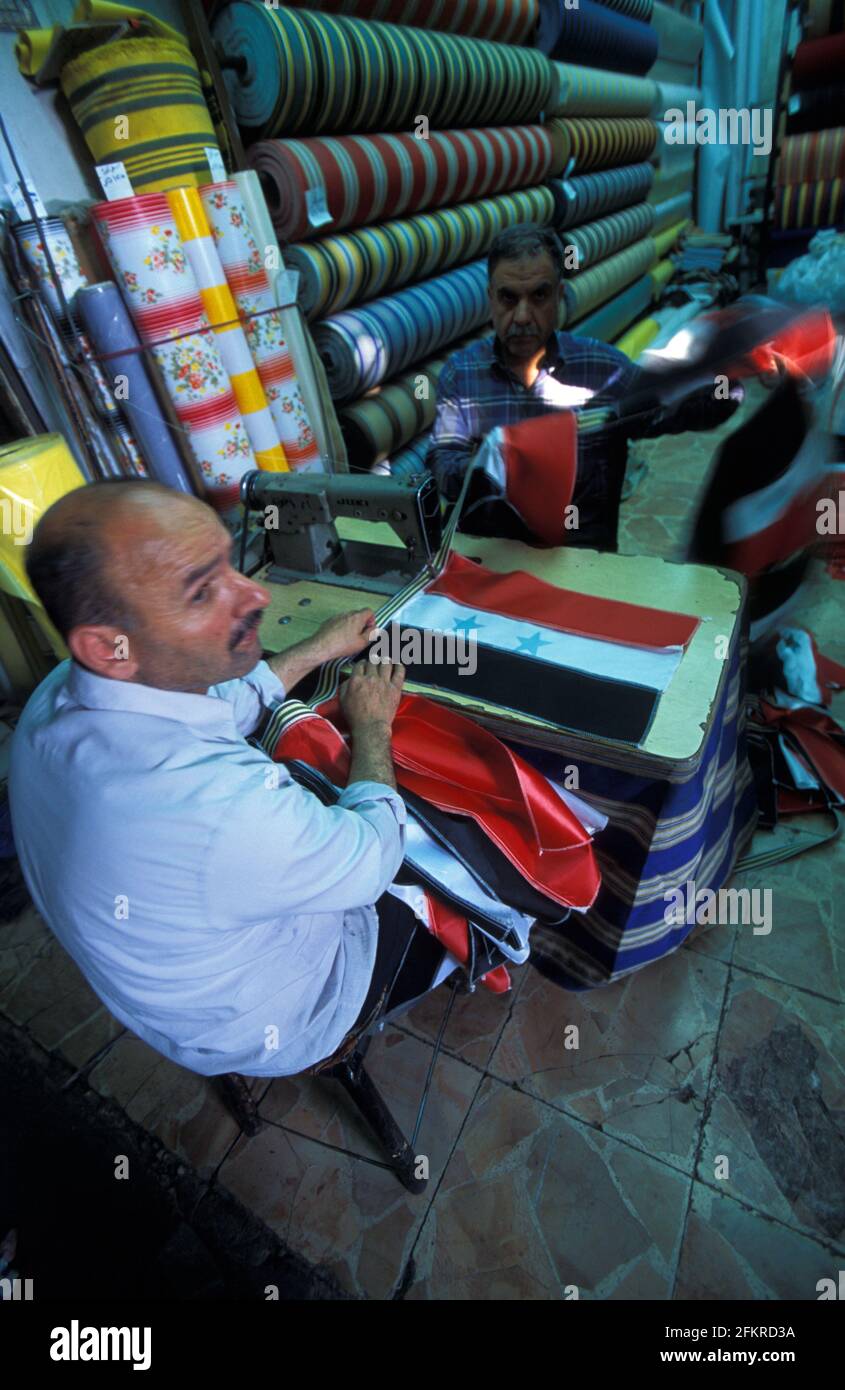 Man sewing a Syrian flag in  a fabric shop in Al-Hamidiyah Souq, Damascus, Syria Stock Photo