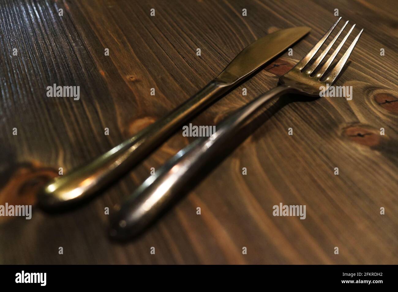 Brass fork and knife on rustic wood top Stock Photo