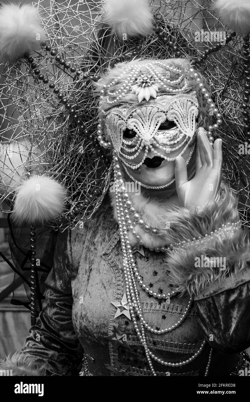 Vertical grayscale shot of a female in a mask and costume Stock Photo