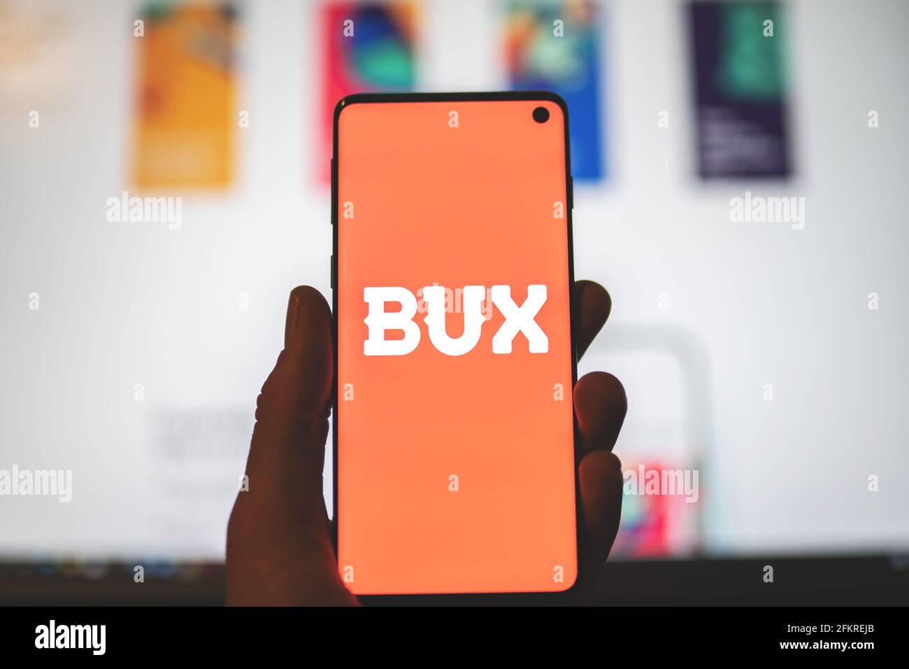Man holding a smartphone with BUX app logo with blurred website background. Mobile investing app, brokerage company in Europe Stock Photo