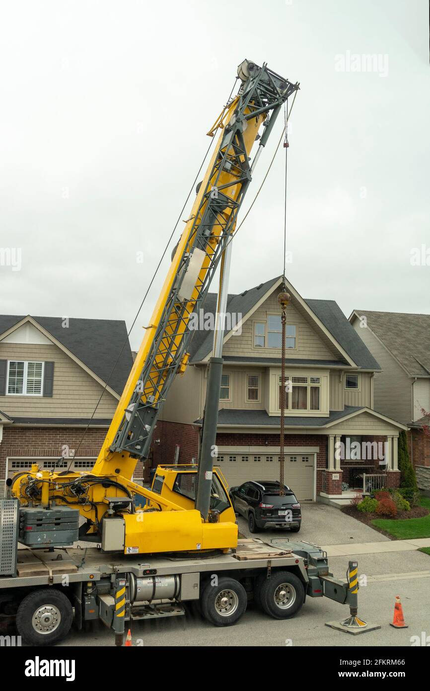 Preparing the crane for work in a residential area next to one of the houses Stock Photo