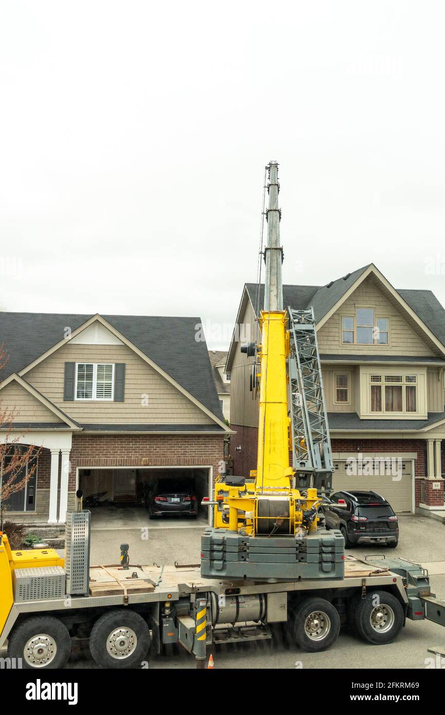 The boom of the crane carries the load over the roof and lowers it behind the house Stock Photo