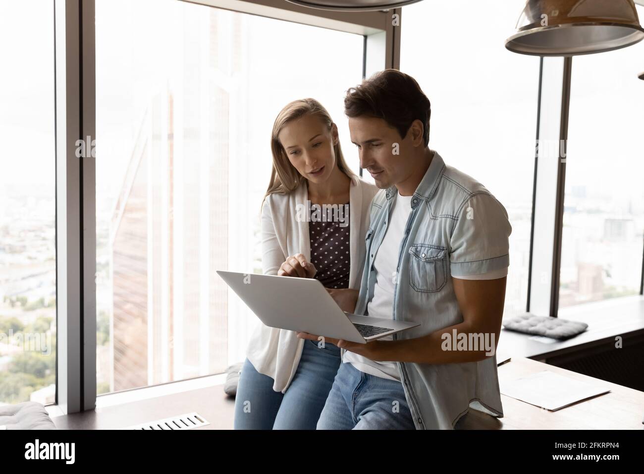 Successful young employees cooperate on laptop in office Stock Photo