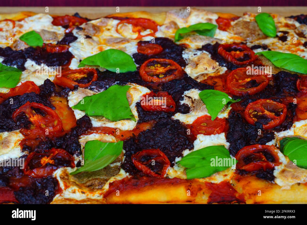 Homemade pizza with olive tapenade and fresh basil leaves Stock Photo