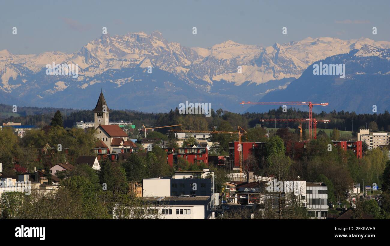 Church of Wetzikon and snow capped mountains. Stock Photo