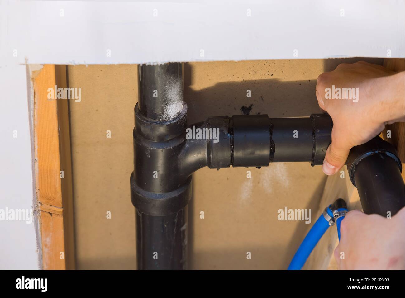 Plumber jointing glue PVC sewage drain pipes on a house under