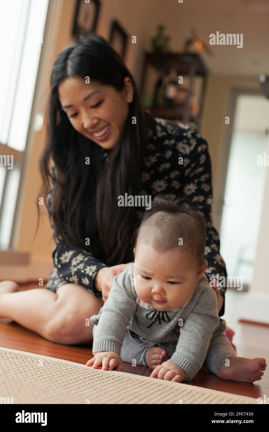 Baby girl sitting on floor with mother Stock Photo - Alamy