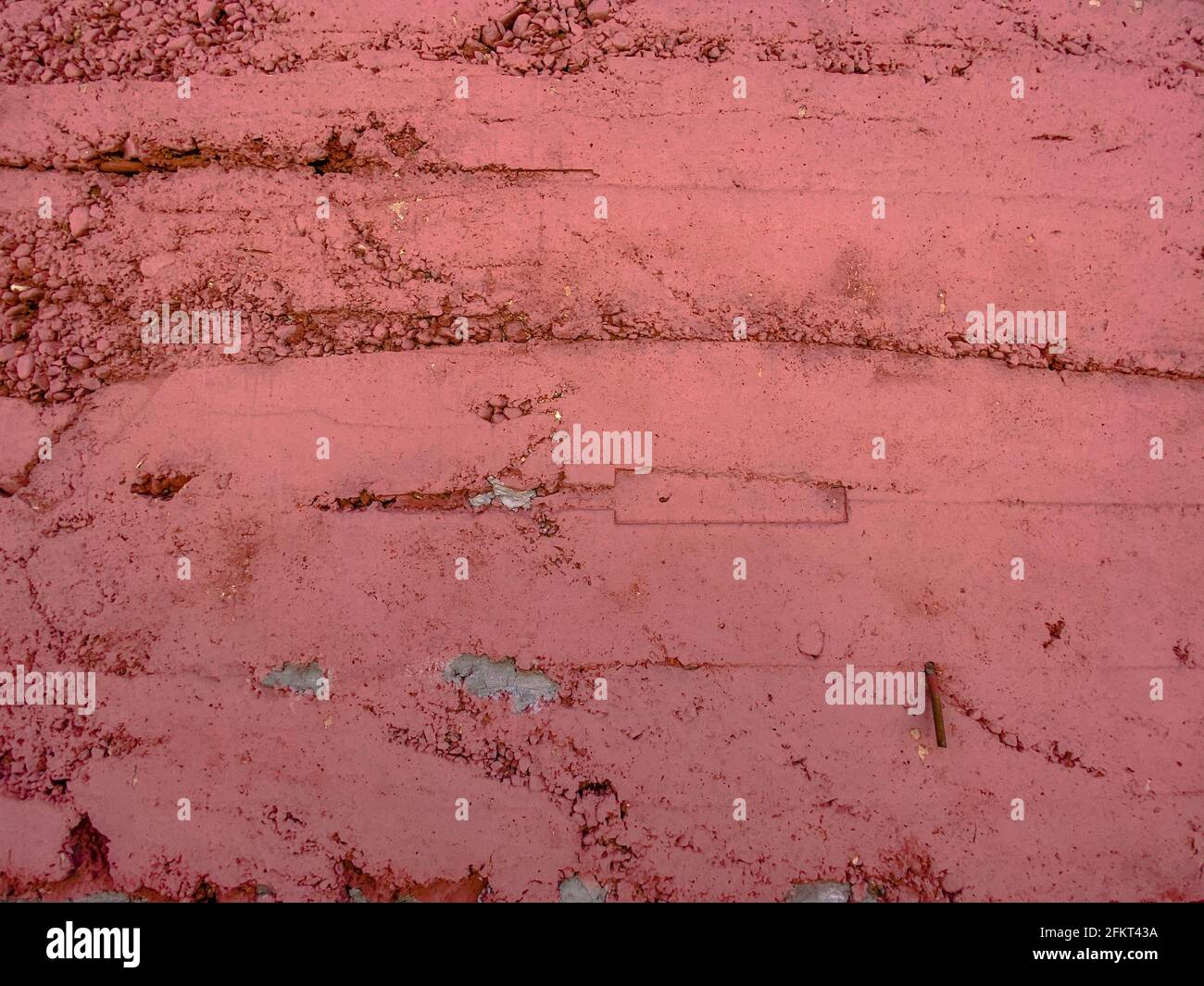old stone block brick garden wall building painted red and weathered Stock Photo