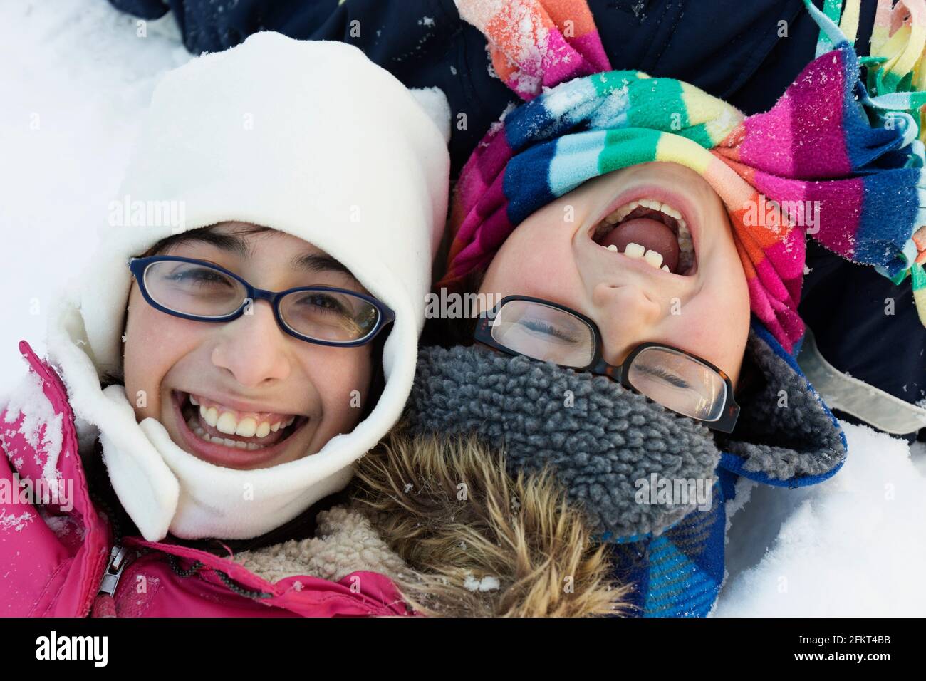 Boy and girl wearing winter hats and glasses, laughing Stock Photo