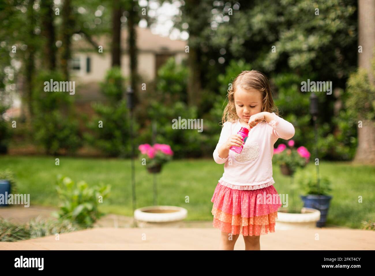 Female toddler preparing to blow bubbles in garden Stock Photo
