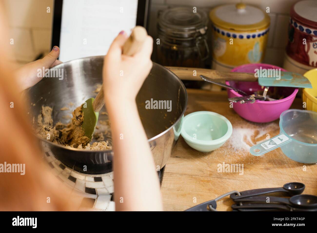 Over shoulder view of girls hand mixing in kitchen bowl Stock Photo