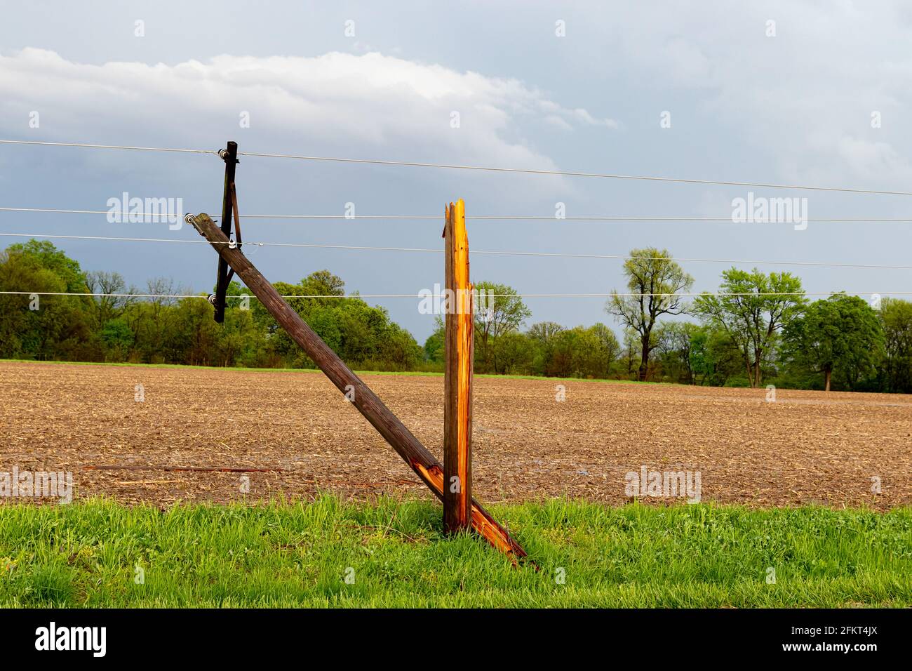 Broken electrical utility pole and power lines due to severe weather. Concept of storm damage, power outage, and electricity danger. Stock Photo