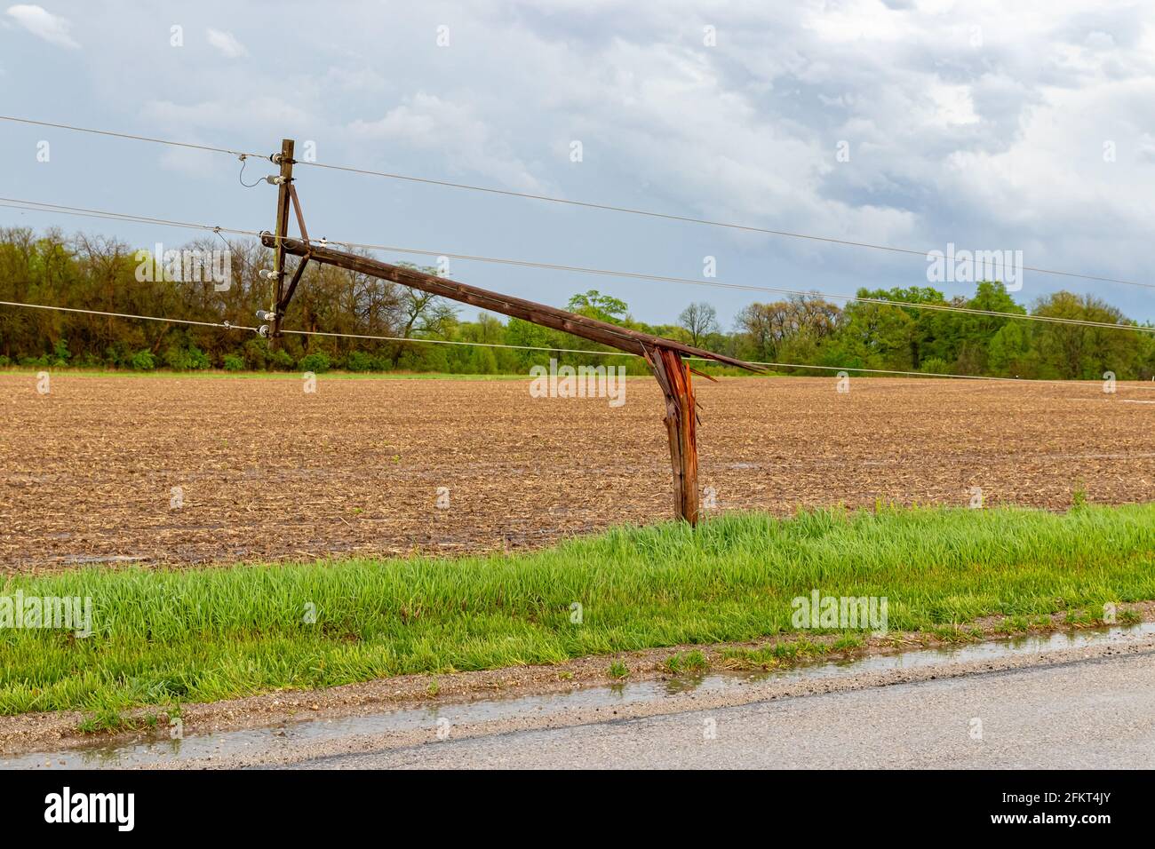 Broken electrical utility pole and power lines due to severe weather. Concept of storm damage, power outage, and electricity danger. Stock Photo