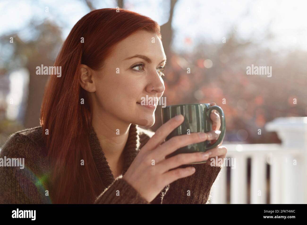 Young woman drinking coffee and gazing out from porch Stock Photo - Alamy