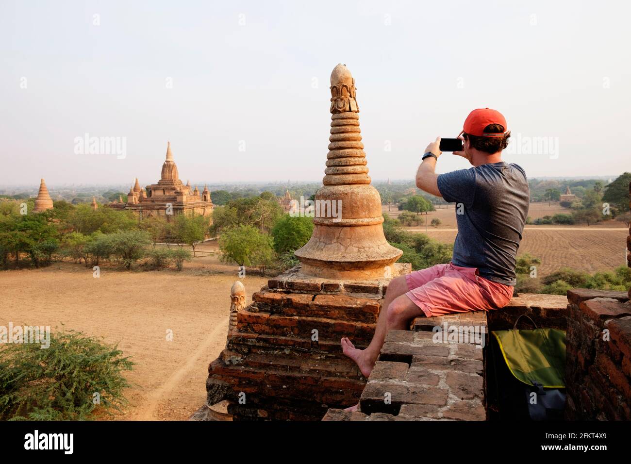 Man taking photograph from stone wall, Bagan Archaeological Zone, Buddhist temples, Mandalay, Myanmar Stock Photo