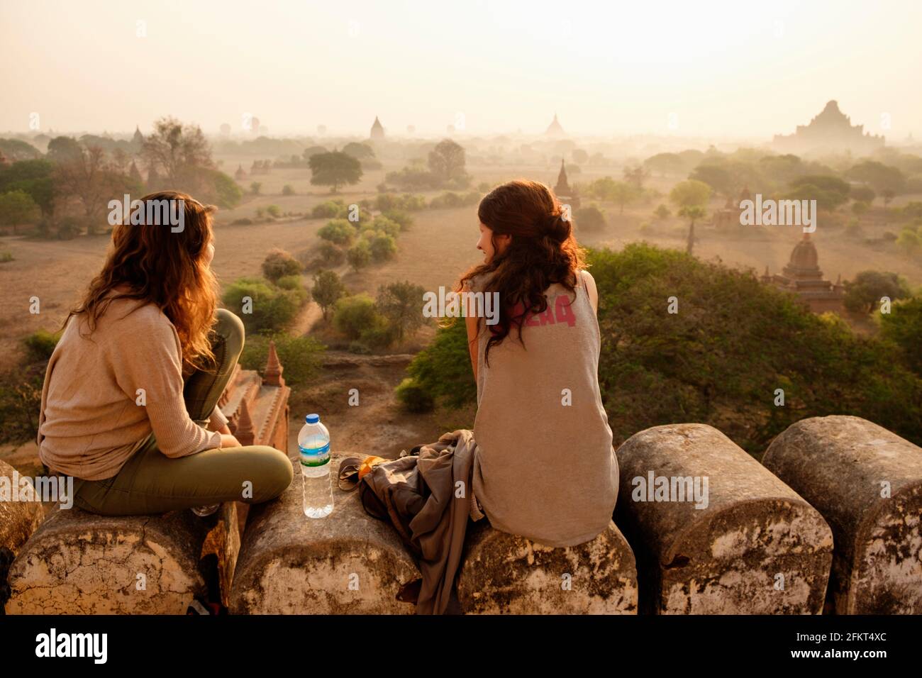 Women relaxing on stone wall, Bagan Archaeological Zone, Buddhist temples, Mandalay, Myanmar Stock Photo