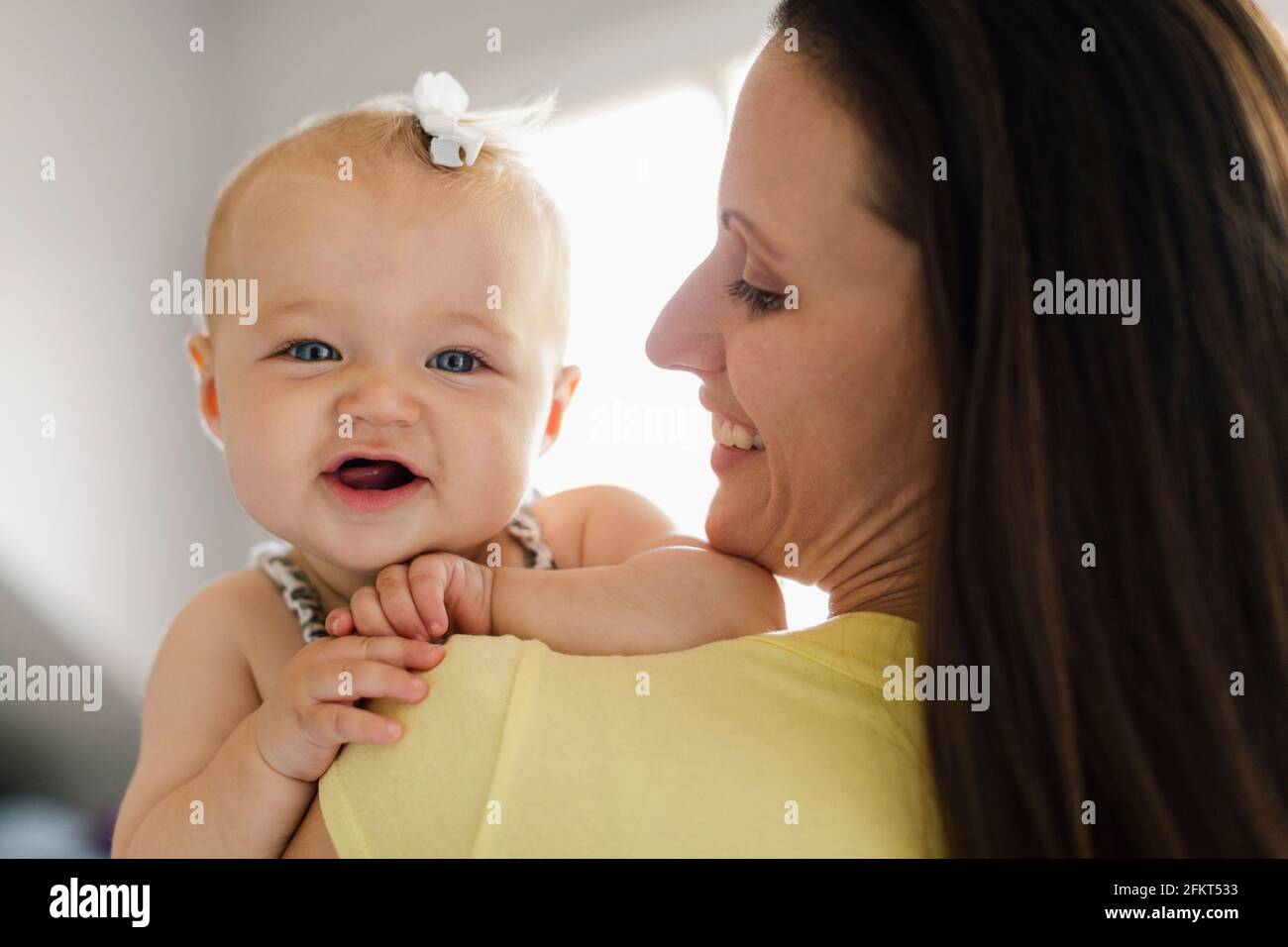 Over the shoulder portrait view of happy baby girl and mid adult mother Stock Photo