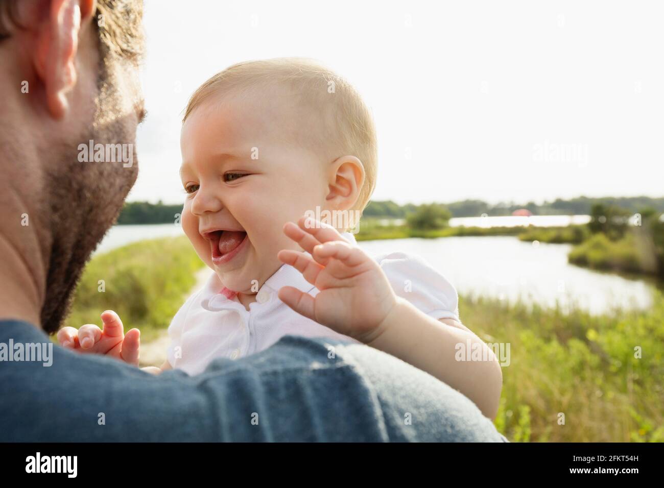 Over shoulder view of mid adult man carrying baby daughter on riverside Stock Photo