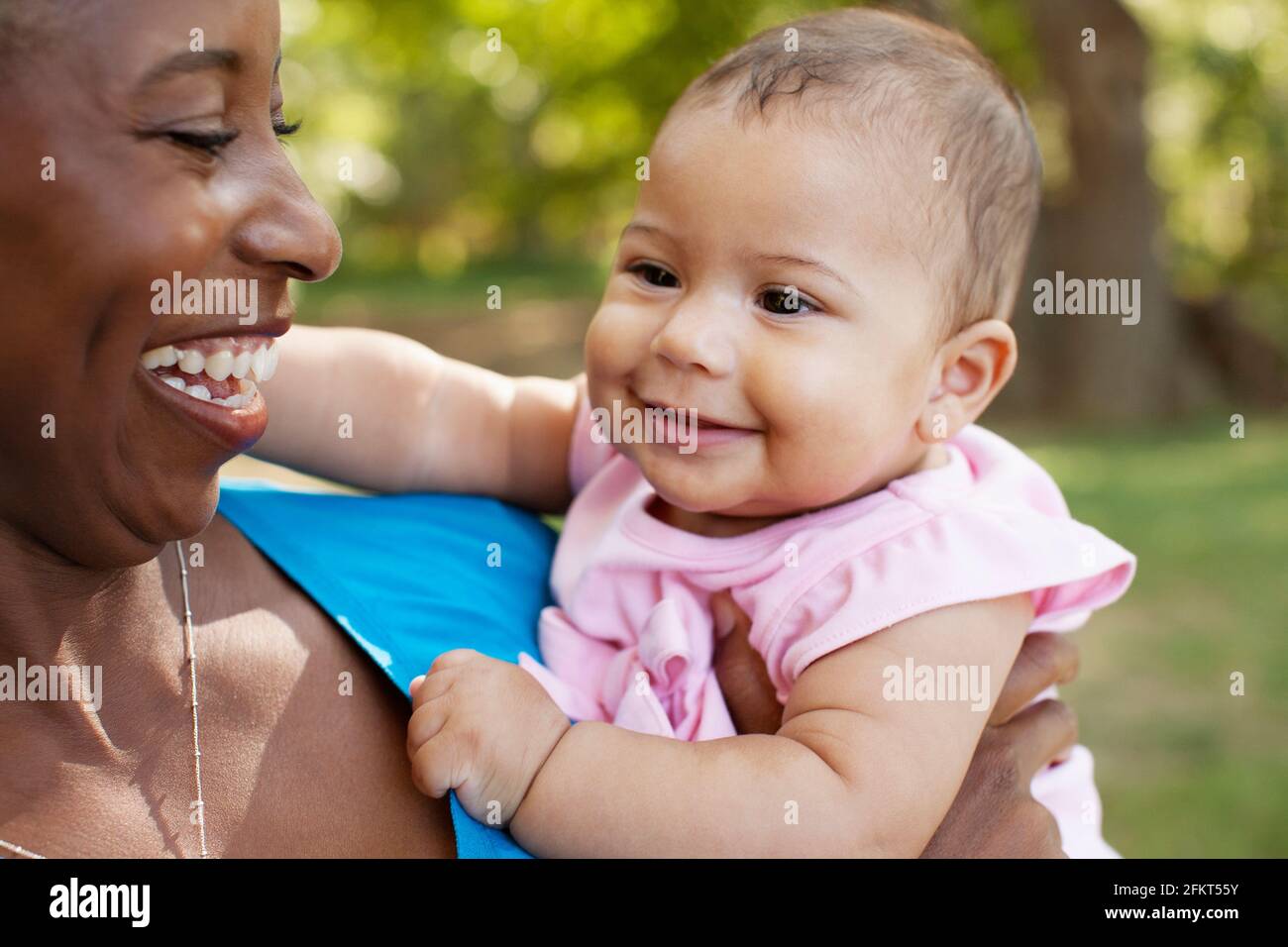 Head and shoulders of mother holding baby girl looking away smiling Stock Photo Alamy
