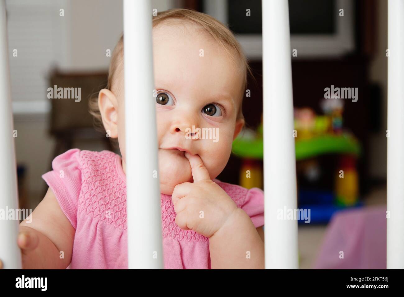 Baby girl, looking through bars on cot Stock Photo Alamy