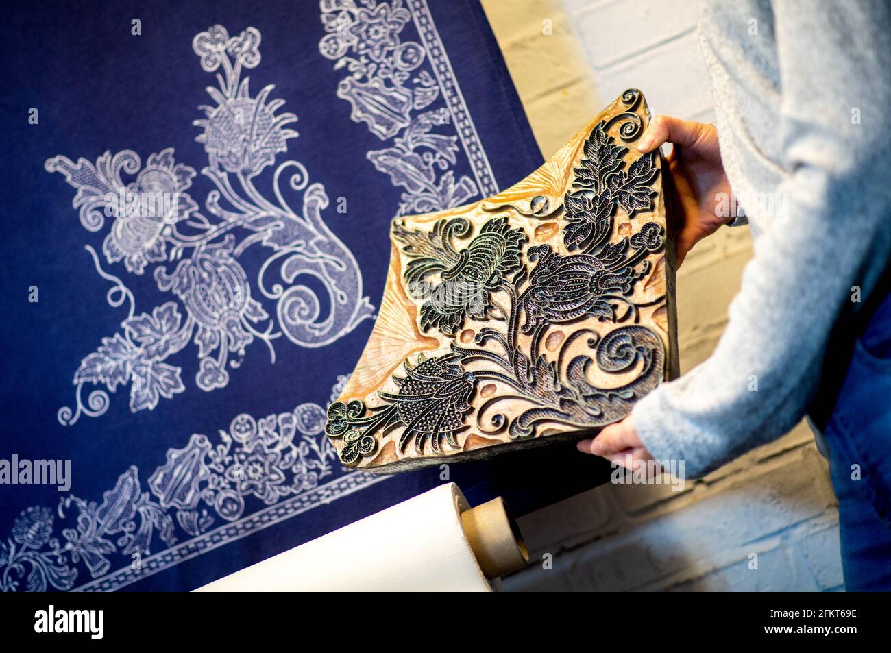 Jever, Germany. 29th Mar, 2021. In her workshop, blue printmaker Sabrina Schuhmacher holds a historical printing block, a so-called model, in front of a blue-dyed fabric with the same pattern. The young fashion designer has taken over the historic blue print workshop in the Frisian town of Jever and wants to keep the old craft alive. (to dpa 'Old craft in young hands - The blue wonder of Jever') Credit: Hauke-Christian Dittrich/dpa/Alamy Live News Stock Photo