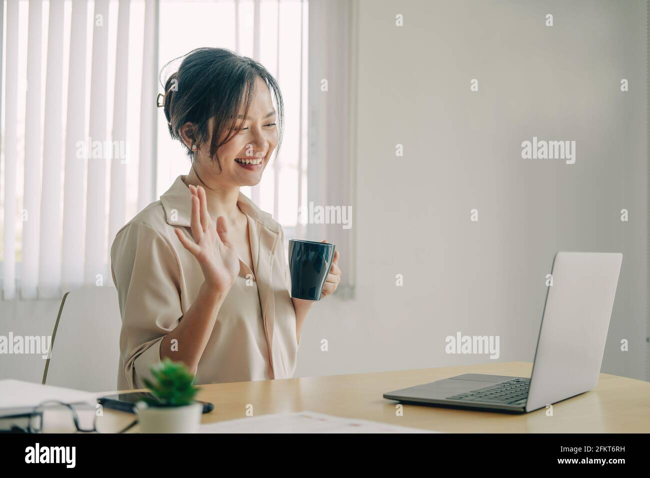 Attractive asian woman having video call via laptop at home office ...