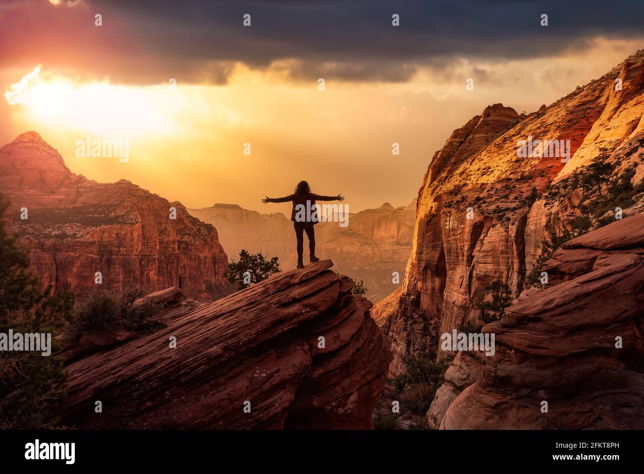 Adventurous Woman at the edge of a cliff is looking at a beautiful ...