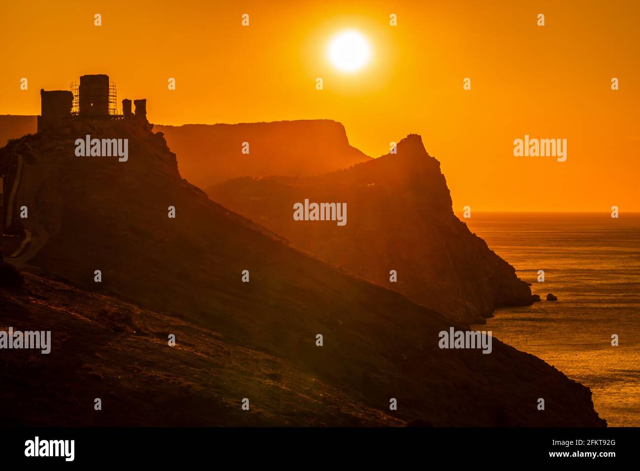 A red burning sunset with the silhouett of a cliff and castle over the ...