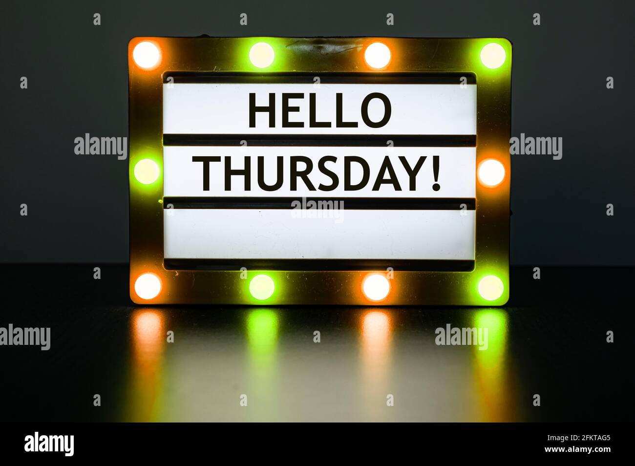 Lightbox with yellow and orange lights in dark room with words - Hello Thursday! Stock Photo