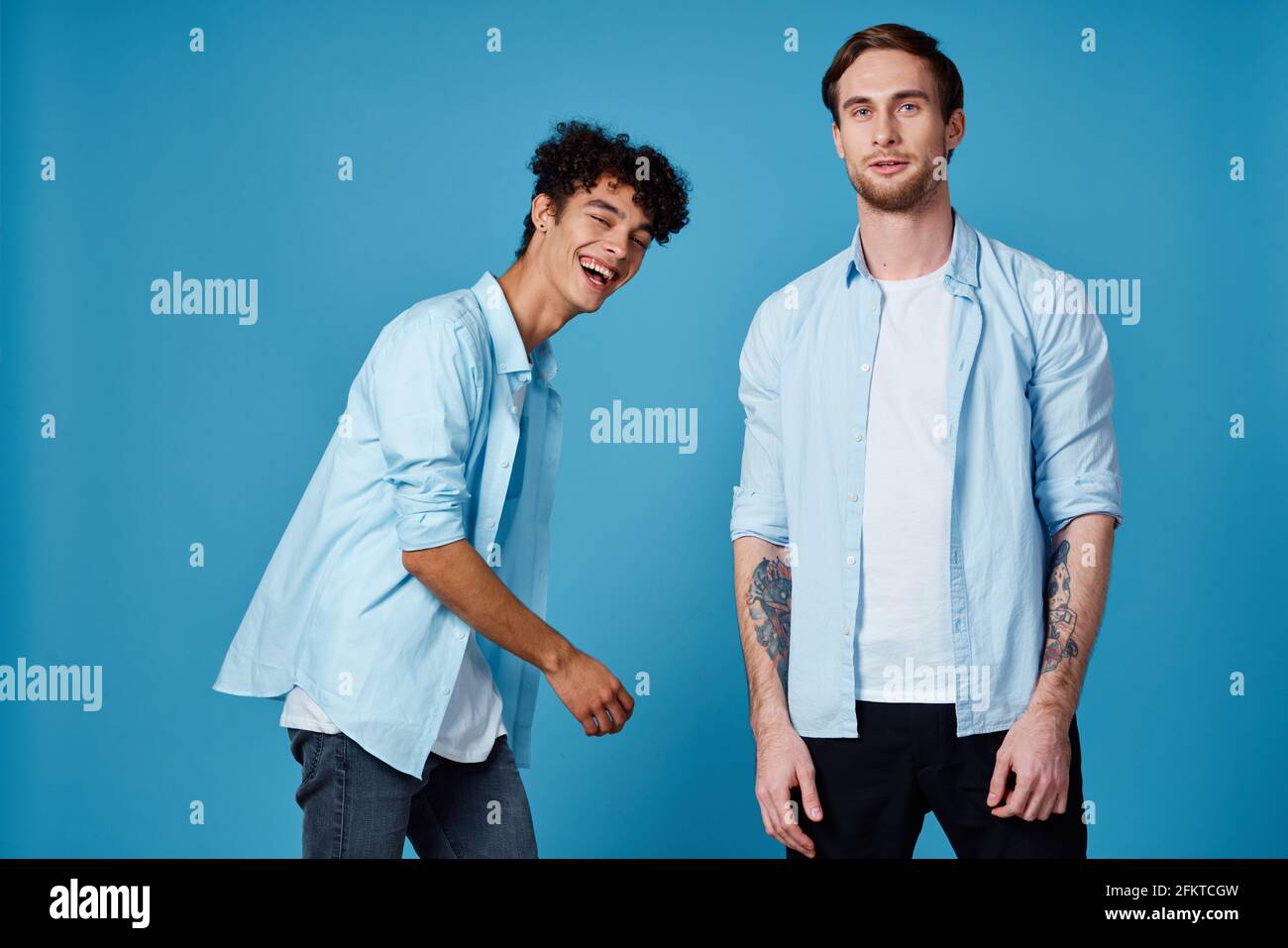 friends in unbuttoned shirts and white t-shirts jeans blue background fun  communication party Stock Photo - Alamy