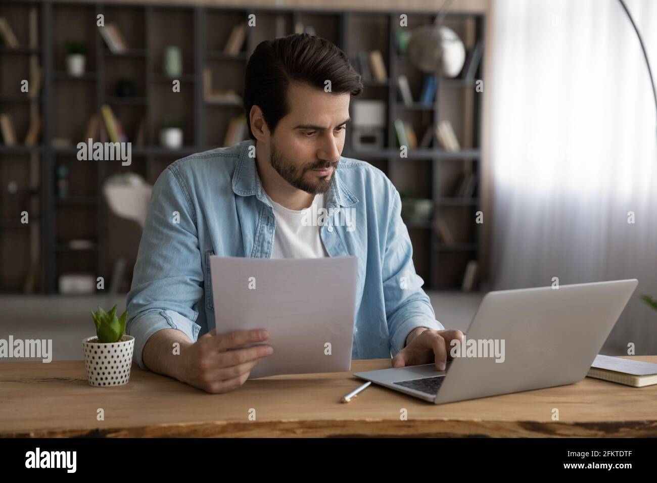 Focused businessman using laptop, working with financial documents, research project Stock Photo