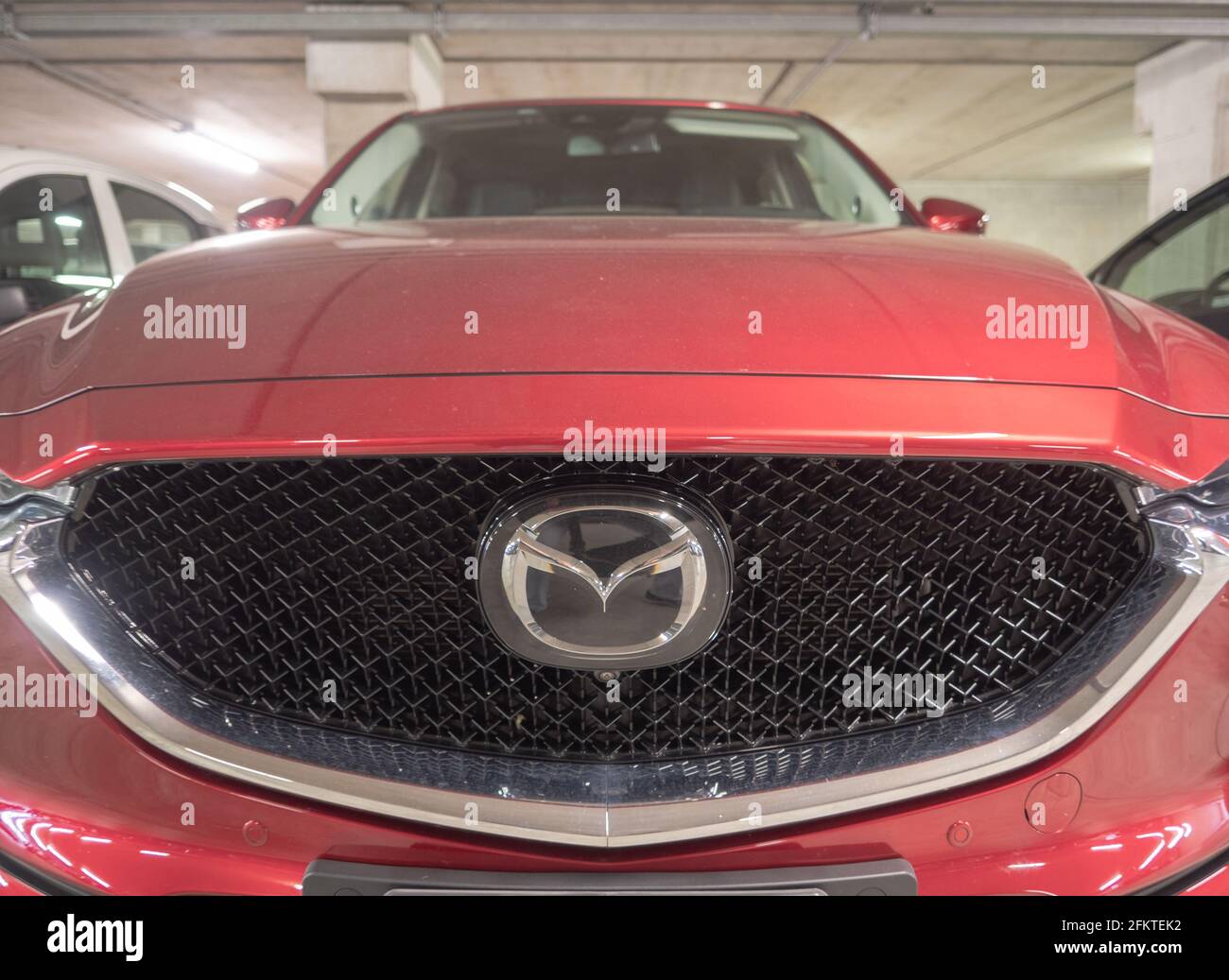large radiator grid in the aggressive front of a red Mazda hybrid Stock Photo