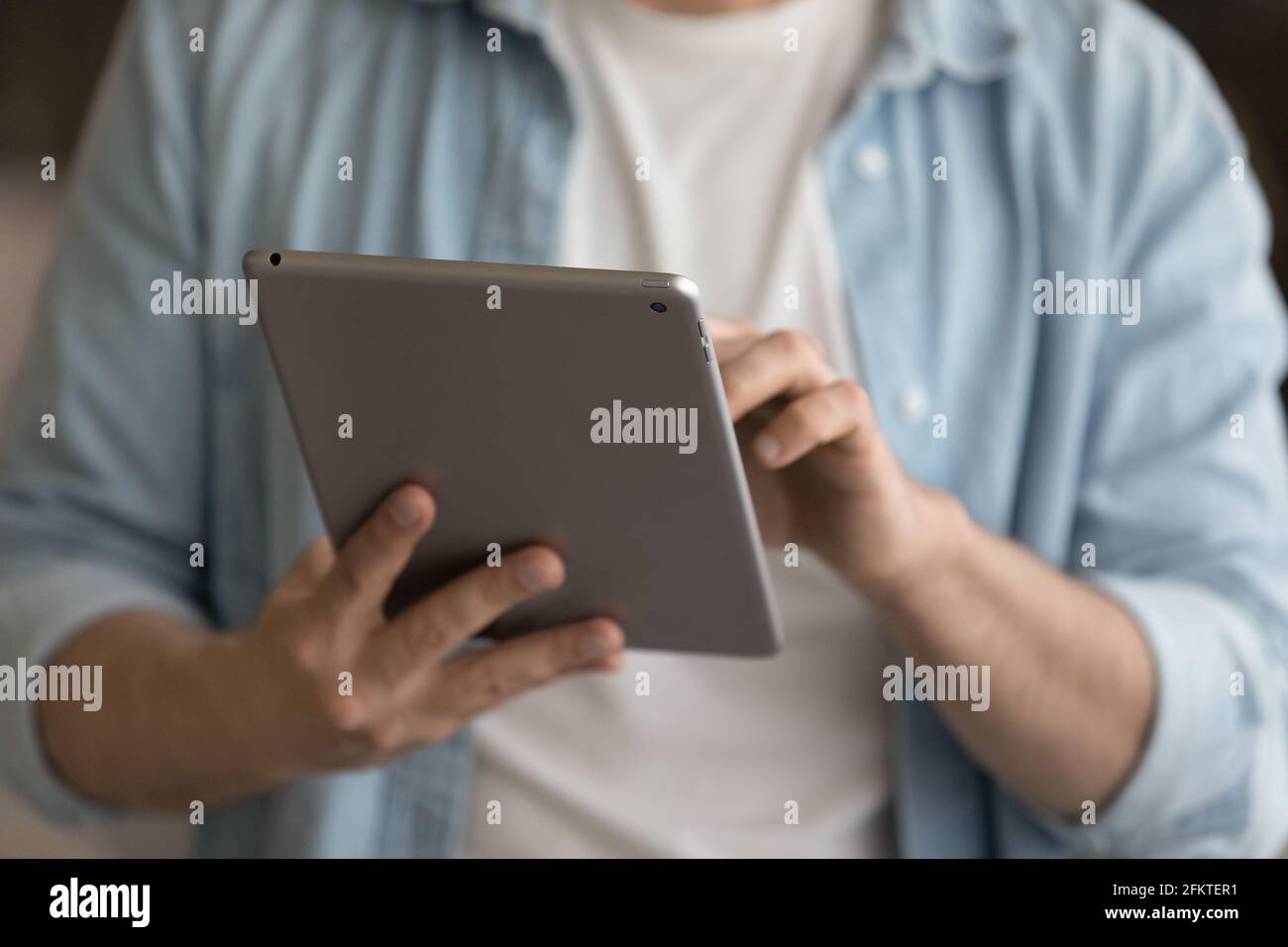 Close up man holding tablet, typing on screen, browsing apps Stock Photo