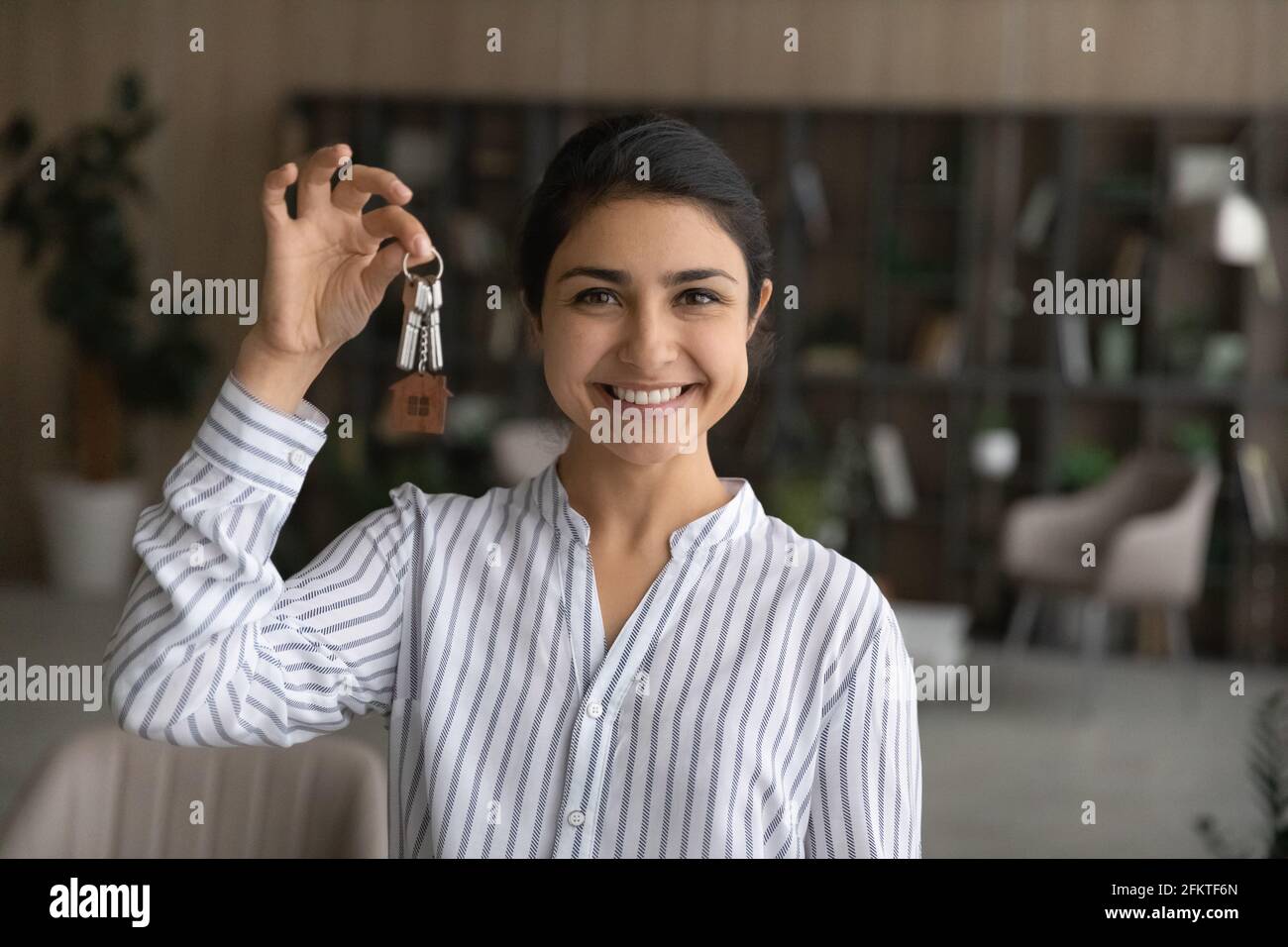 Head shot portrait smiling Indian woman showing keys, rejoicing relocation Stock Photo
