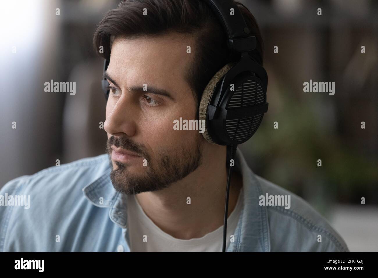 Close up dreamy man in headphones looking to aside Stock Photo