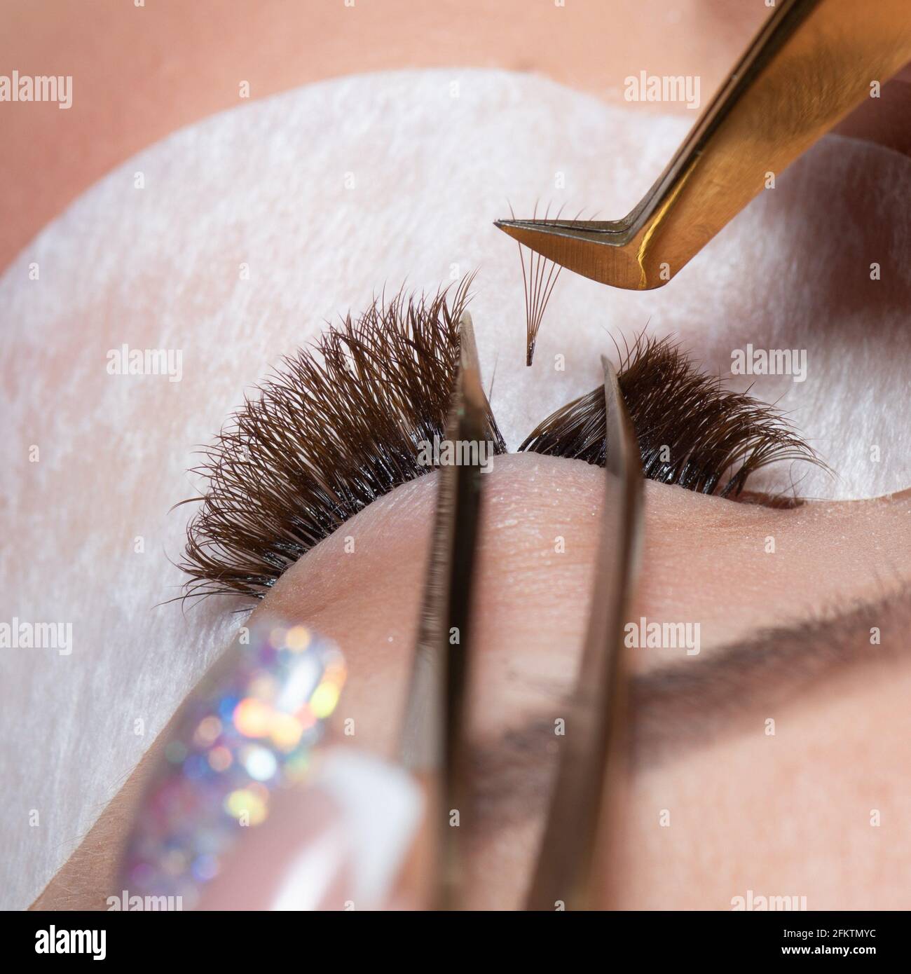 Eyelash Extension Procedure. Woman Eye with Long Eyelashes. Lashes. Close up tweezers, macro, selective focus. Stock Photo