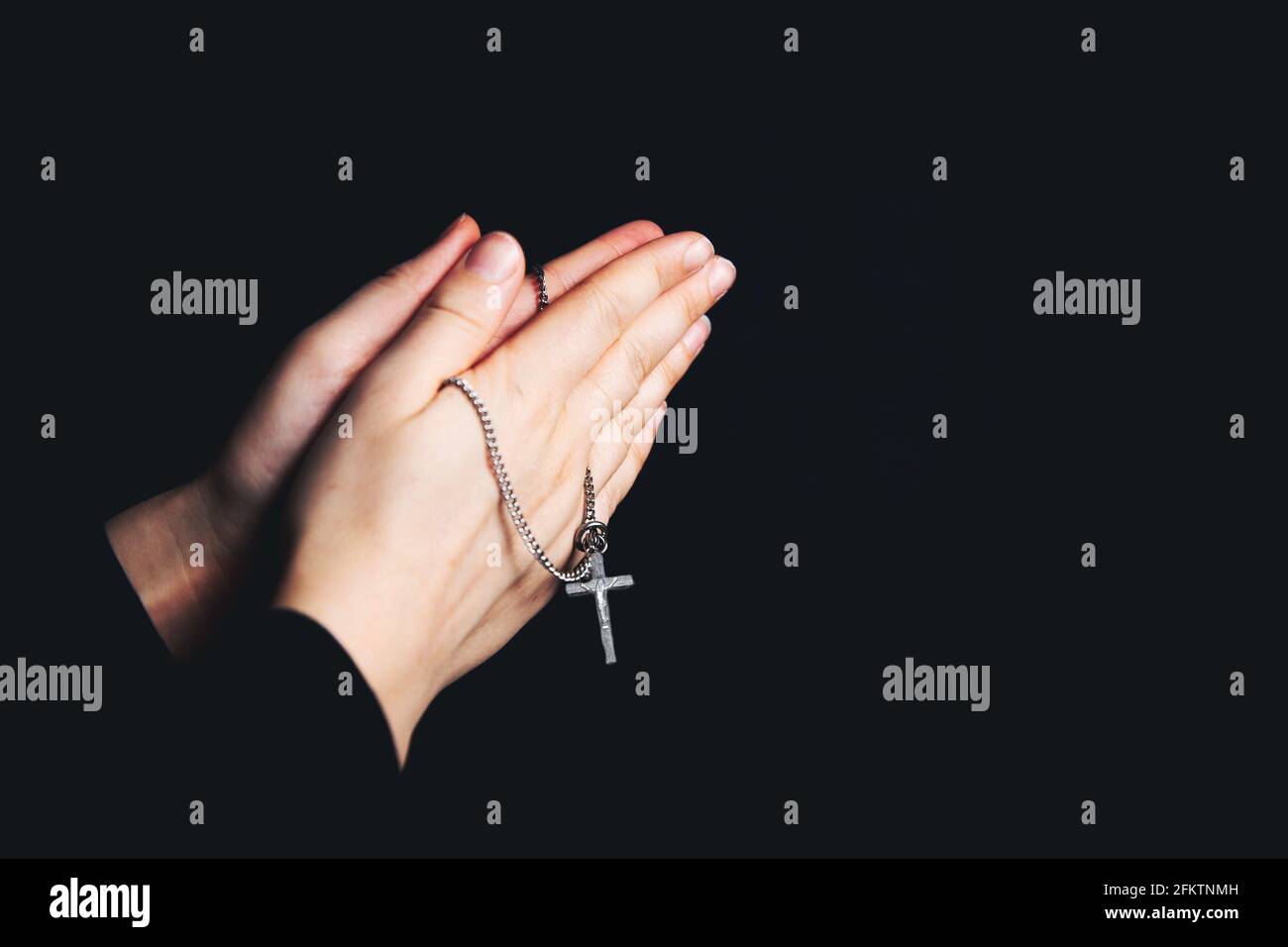 Praying hands holding a rosary, Closeup holding necklace with cross,pray for god in the dark, religious Christian symbol with copy space background. Stock Photo