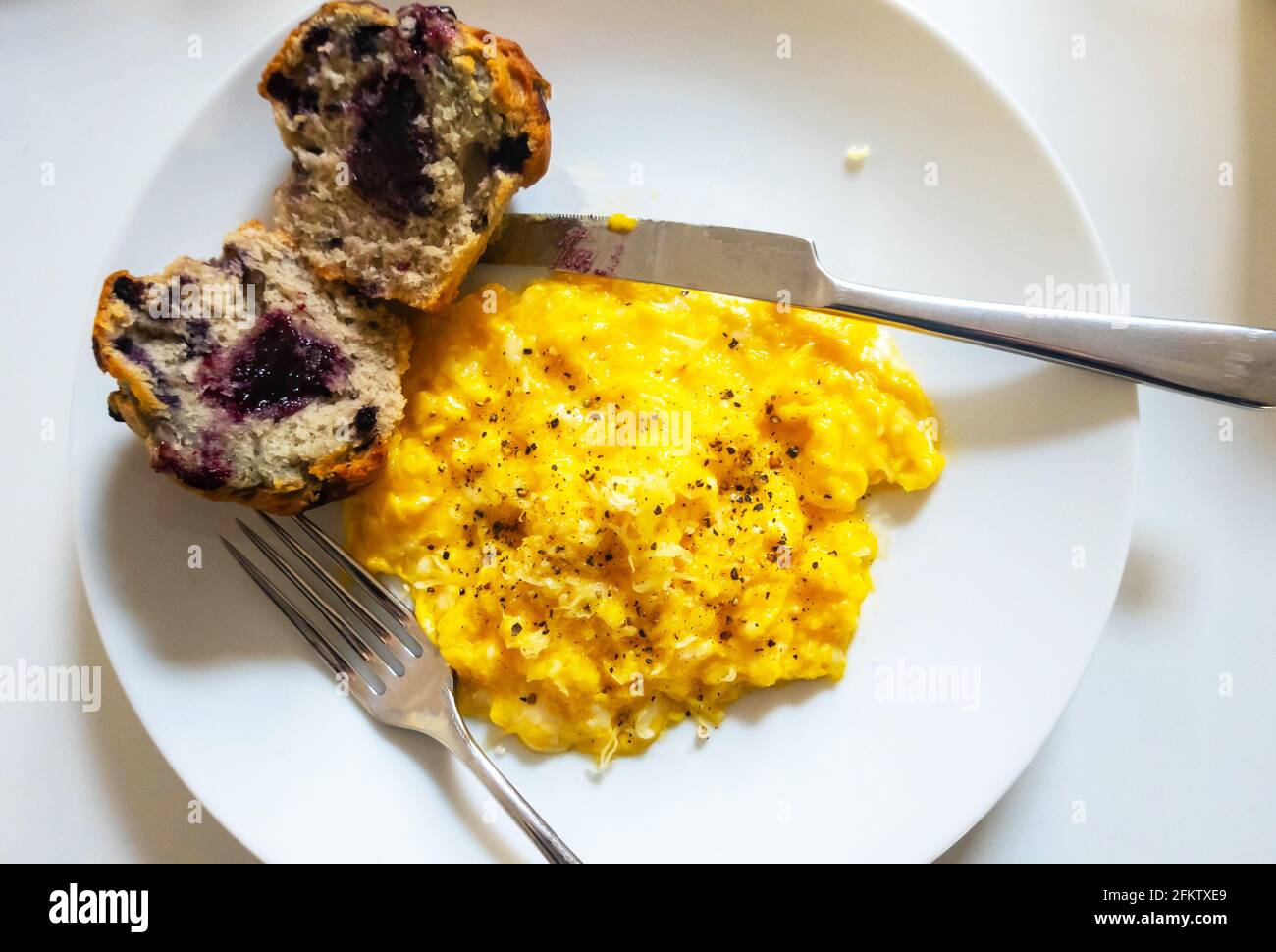 Scrambled eggs with cheddar cheese and a blueberry muffin Stock Photo