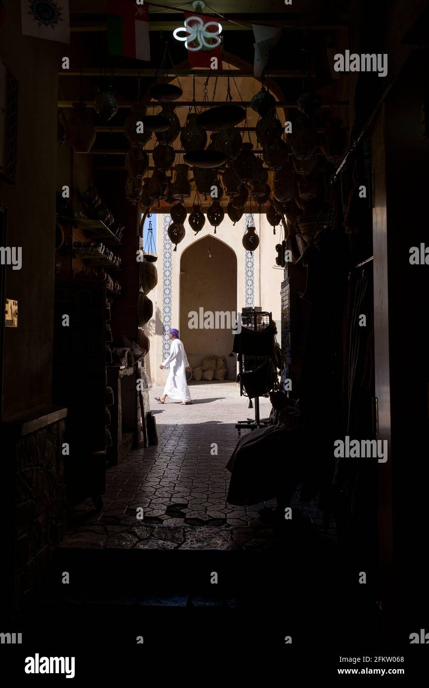 View from a pottery shop in the souq of Nizwa on a man passing in the street.. Ad Dakhiliyah Region, Oman Stock Photo