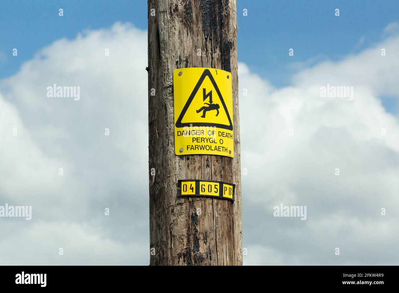 Electricity power line with prominent warning sign in English and Welsh langauges warning of electrocution and danger of death Stock Photo